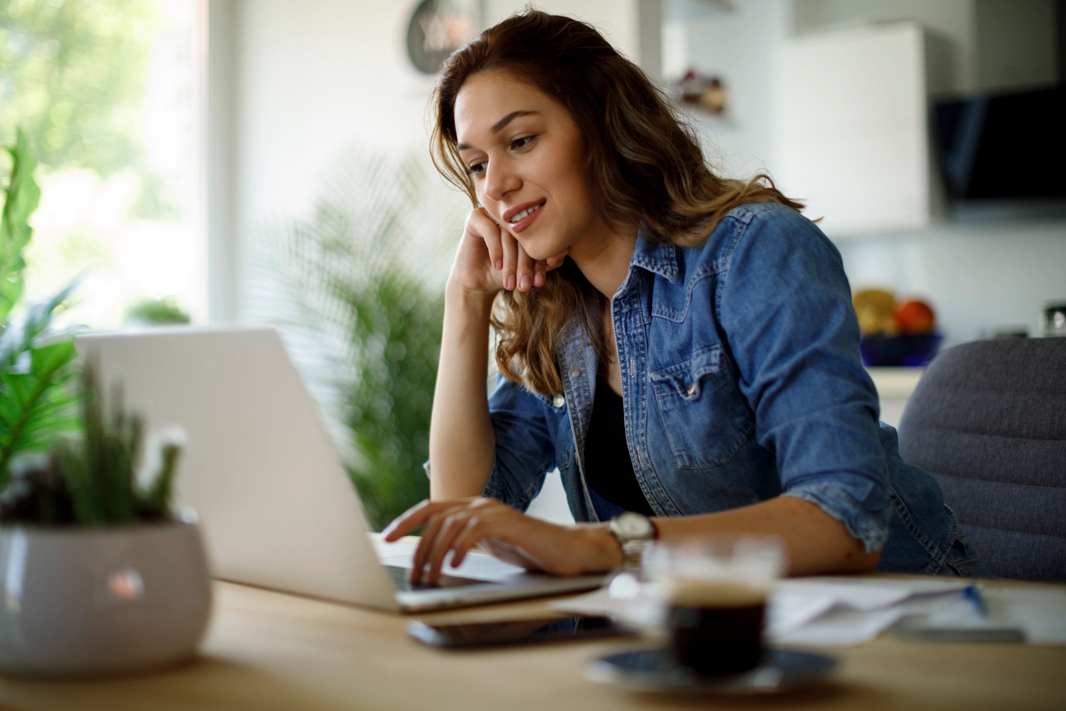 Freelancer researching home loans on laptop, smiling confidently in home office setting