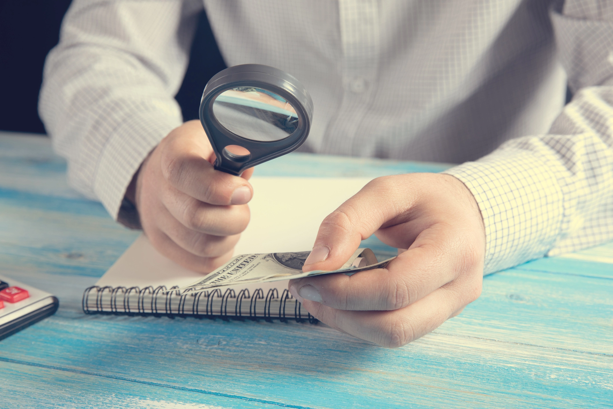 Person examining refinance offer details with magnifying glass